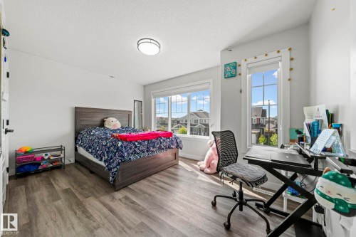 Light-filled room featuring durable wood-finish flooring, a contemporary ceiling fixture, and dual windows - 16128 31 Avenue Sw, Edmonton, AB - Indoor Photo Showing Bedroom
