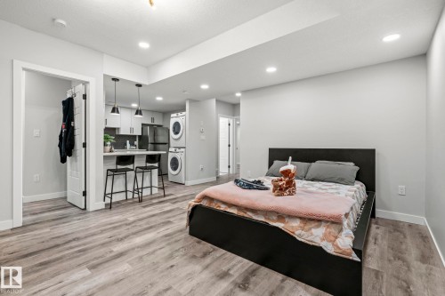 Wood-finish flooring throughout, recessed lighting, and a kitchen featuring white cabinetry, pendant lighting, and a breakfast bar - 16128 31 Avenue Sw, Edmonton, AB - Indoor Photo Showing Bedroom