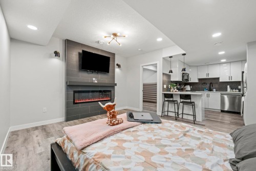 Integrated kitchen with white cabinetry and stainless steel appliances - 16128 31 Avenue Sw, Edmonton, AB - Indoor Photo Showing Living Room With Fireplace