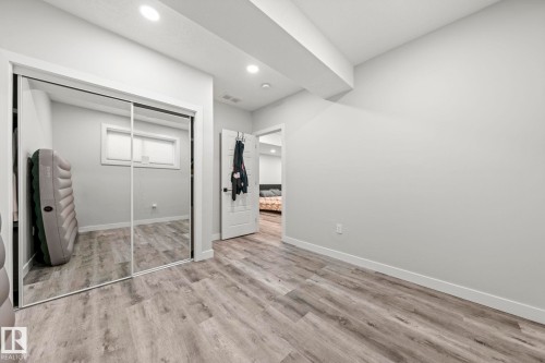 Wood-finish flooring, recessed lighting, and a mirrored sliding closet door - 16128 31 Avenue Sw, Edmonton, AB - Indoor Photo Showing Other Room