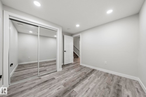 Wood-finish flooring, recessed lighting, white trim, mirrored closet doors, and a paneled interior door - 16128 31 Avenue Sw, Edmonton, AB - Indoor