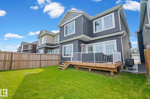 Expansive green lawn, wood fence, wood-finish deck with white railing, and dual-pane windows - 16128 31 Avenue Sw, Edmonton, AB - Outdoor With Deck Patio Veranda