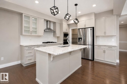 Kitchen featuring a large island with sink, stainless steel appliances, light-toned cabinetry, and wood-finish flooring - 7274 Morgan Road Nw, Edmonton, AB - Indoor Photo Showing Kitchen With Upgraded Kitchen
