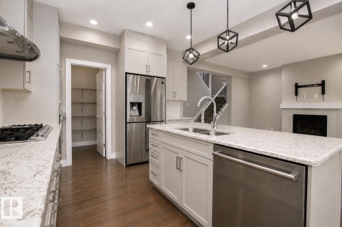 Kitchen featuring an island with dual sinks, light-toned countertops, shaker-style cabinetry, and stainless steel appliances - 7274 Morgan Road Nw, Edmonton, AB - Indoor Photo Showing Kitchen With Double Sink With Upgraded Kitchen