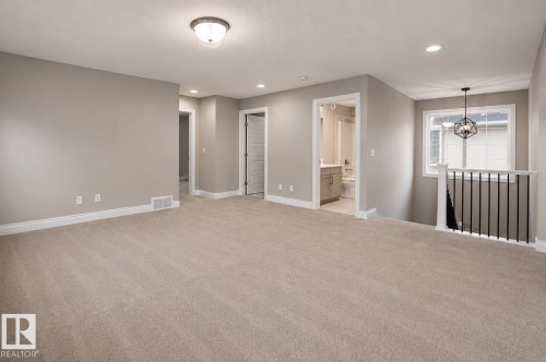 Neutral tone carpeting throughout, recessed lighting, ceiling-mounted light fixture, white trim, and a window with a decorative hanging fixture - 7274 Morgan Road Nw, Edmonton, AB - Indoor Photo Showing Other Room