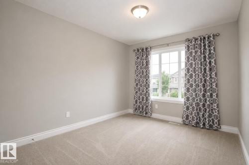 Neutral-toned carpeting and walls, trim work, and a double-paned window with gridded panes - 7274 Morgan Road Nw, Edmonton, AB - Indoor Photo Showing Other Room