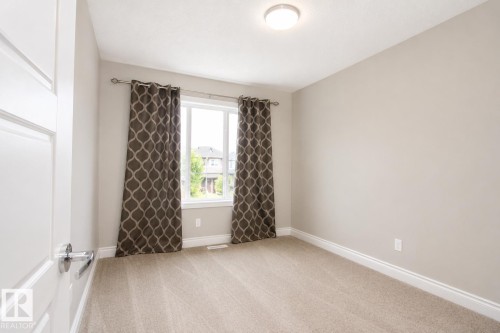 Neutral wall paint, carpet flooring, a window with curtains, and a flush-mount ceiling light - 7274 Morgan Road Nw, Edmonton, AB - Indoor Photo Showing Other Room