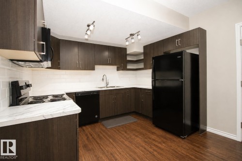 Modern kitchen featuring wood-finish cabinetry, white subway tile backsplash, white countertops, and stainless steel sink with a gooseneck faucet - 7274 Morgan Road Nw, Edmonton, AB - Indoor Photo Showing Kitchen