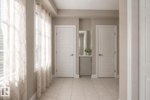 Neutral tone wall paint, light-colored tile flooring, multiple panel doors, and a built-in counter with a mirror - 7274 Morgan Road Nw, Edmonton, AB - Indoor Photo Showing Other Room
