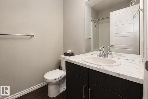 White-patterned countertop with an integrated oval sink, dark wood-finish vanity, chrome hardware, and wood-finish flooring - 7274 Morgan Road Nw, Edmonton, AB - Indoor Photo Showing Bathroom