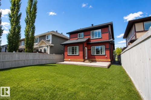 Expansive grassy yard featuring a wood privacy fence, a ground-level deck, and a red exterior with white-trimmed windows - 7274 Morgan Road Nw, Edmonton, AB - Outdoor