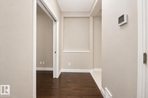 Warm neutral wall paint, wood-finish flooring, white trim, and a wall-mounted thermostat - 7274 Morgan Road Nw, Edmonton, AB - Indoor Photo Showing Other Room