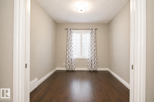 Warm wood-finish flooring, neutral wall paint, white window shutters, and a ceiling-mounted light fixture - 7274 Morgan Road Nw, Edmonton, AB - Indoor Photo Showing Other Room