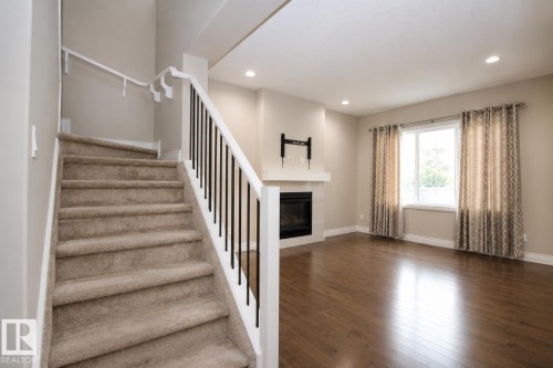 Carpeted staircase with white railings and black balusters - 7274 Morgan Road Nw, Edmonton, AB - Indoor With Fireplace