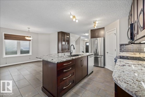 Kitchen featuring a granite-topped island with an undermount sink and dark wood cabinetry - 1086 Grantham Drive Nw, Edmonton, AB - Indoor Photo Showing Kitchen With Upgraded Kitchen