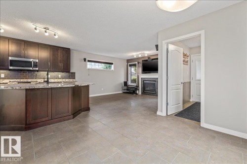 Open-concept living area featuring large format tile flooring and a kitchen island with stone countertops - 1086 Grantham Drive Nw, Edmonton, AB - Indoor Photo Showing Kitchen