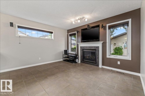 Living area featuring a fireplace with a decorative mantel and dark tile surround - 1086 Grantham Drive Nw, Edmonton, AB - Indoor Photo Showing Living Room With Fireplace