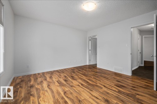 Spacious room featuring wood-finish flooring, white baseboards, and a neutral wall palette - 1086 Grantham Drive Nw, Edmonton, AB - Indoor Photo Showing Other Room