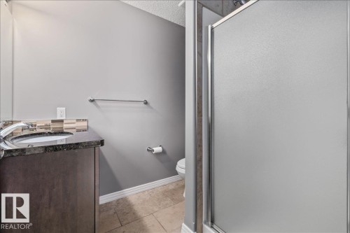 Bathroom vanity with dark wood-finish cabinetry, a polished dark countertop, and a vessel sink with a chrome faucet - 1086 Grantham Drive Nw, Edmonton, AB - Indoor Photo Showing Bathroom