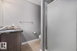 Bathroom vanity with dark wood-finish cabinetry, a polished dark countertop, and a vessel sink with a chrome faucet - 