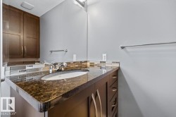 Bathroom vanity featuring a polished stone countertop with an integrated oval sink, chrome-finish faucet, and a tiled backsplash - 