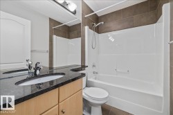 Bathroom featuring a vanity with a dark countertop, an undermount sink, and a chrome faucet - 