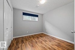 Room featuring wood-finish flooring, light grey painted walls, white baseboards, and a white ceiling with a flush-mount light fixture - 