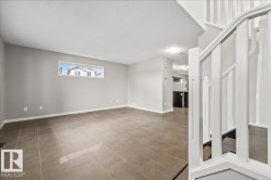 Open-concept living area with neutral gray walls and large format tile flooring - 