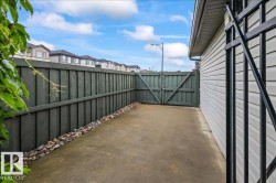 Concrete patio area featuring a wooden privacy fence with gate access - 