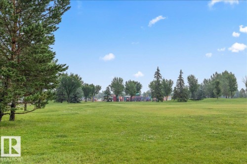 Expansive green space featuring mature trees and a distant playground structure - 1086 Grantham Drive Nw, Edmonton, AB - Outdoor With View