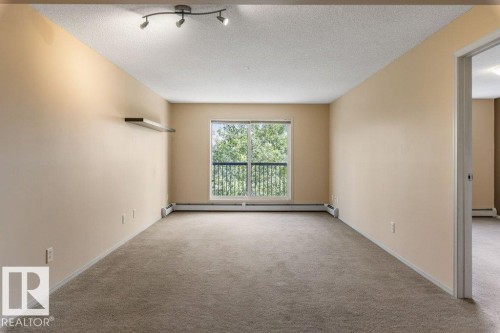 Neutral-toned carpeting throughout - #307 1188 Hyndman Rd Nw, Edmonton, AB - Indoor Photo Showing Other Room