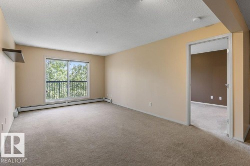 Spacious room with plush carpeting and neutral wall tones - #307 1188 Hyndman Rd Nw, Edmonton, AB - Indoor Photo Showing Other Room