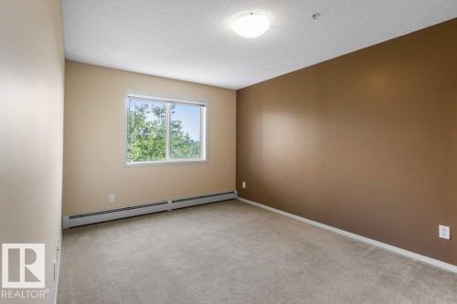 Neutral tone walls, ceiling-mounted light fixture, and window with exterior scenery - #307 1188 Hyndman Rd Nw, Edmonton, AB - Indoor Photo Showing Other Room