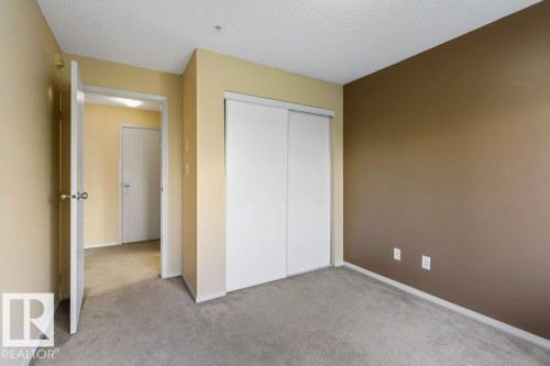 Wall-to-wall carpeting and neutral-toned walls with an accent wall - #307 1188 Hyndman Rd Nw, Edmonton, AB - Indoor Photo Showing Other Room