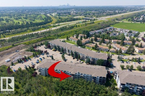 Apartment building with multiple stories, balconies, and an adjacent parking area - #307 1188 Hyndman Rd Nw, Edmonton, AB - Outdoor With View