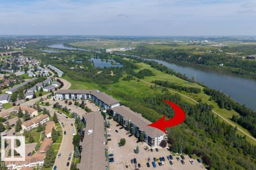 Multi-story residential buildings with surface parking, bordering dense natural landscaping, and a substantial river - #307 1188 Hyndman Rd Nw, Edmonton, AB - Outdoor With Body Of Water With View