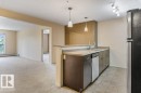 Kitchen featuring stainless steel appliances, dark wood-finish cabinetry, and solid surface countertops - #307 1188 Hyndman Rd Nw, Edmonton, AB  - Indoor Photo Showing Kitchen 