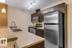 Kitchen featuring stainless steel appliances, dark wood cabinetry, a double basin sink with a high-arc faucet, and track lighting - 