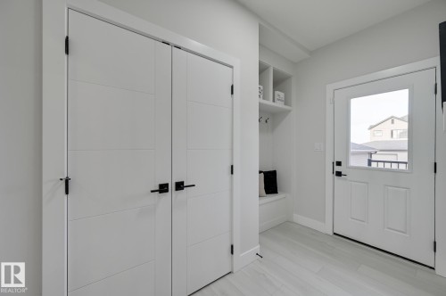 White doors with black hardware, built-in shelving, built-in bench, and wood-finish flooring - 51 Clichy Close, St. Albert, AB - Indoor Photo Showing Other Room