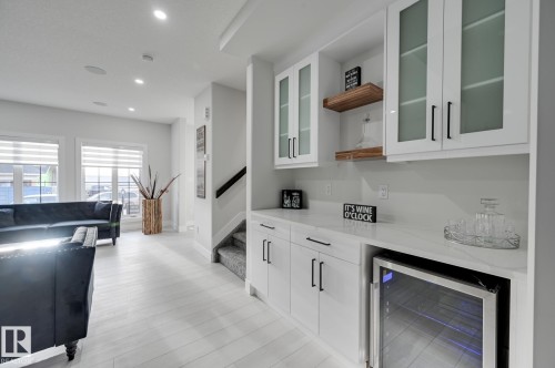 Built-in beverage bar with a wine refrigerator, frosted-glass upper cabinetry, and a light-toned countertop - 51 Clichy Close, St. Albert, AB - Indoor