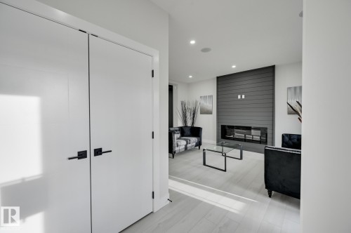 White interior doors with matte black hardware, wood-finish flooring, recessed lighting, and a linear fireplace with a shiplap surround - 51 Clichy Close, St. Albert, AB - Indoor Photo Showing Other Room