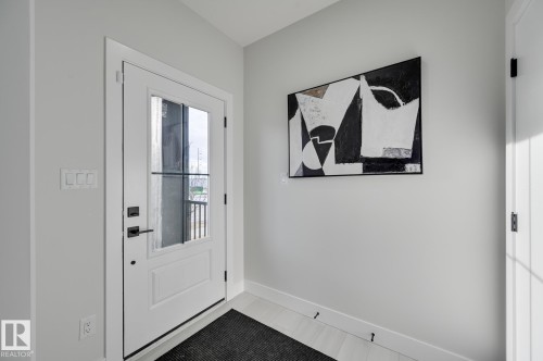 White paneled door with integrated glass panel, matte black hardware, and crisp white trim - 51 Clichy Close, St. Albert, AB - Indoor Photo Showing Other Room