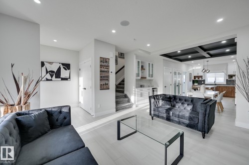 Recessed lighting, wood-finish flooring, staircase with carpeted treads, built-in cabinetry, and a dark coffered ceiling - 51 Clichy Close, St. Albert, AB - Indoor Photo Showing Living Room