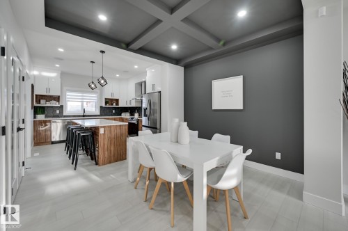 Coffered ceiling, accent wall, wood-finish kitchen island, stainless steel appliances, and light-toned flooring - 51 Clichy Close, St. Albert, AB - Indoor Photo Showing Dining Room