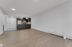 Wood-finish flooring throughout, complemented by a kitchen featuring dark wood cabinetry, a breakfast bar, and stainless steel appliances - 