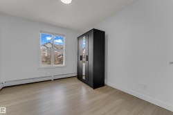 Light wood-finish flooring, white walls, and a large window providing natural light - 