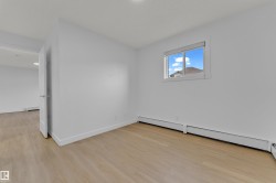 Wood-finish flooring with white baseboards, a white door frame, and a window with white trim - 