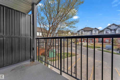 Balcony with black metal railing and privacy screen, concrete flooring, and a corrugated metal ceiling - #217 667 Watt Bv Sw, Edmonton, AB - Outdoor With Balcony