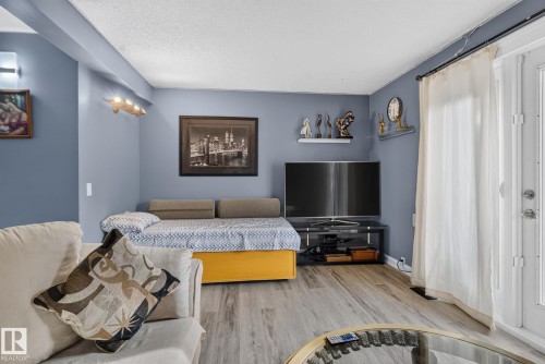 Living area featuring wood-finish flooring, a neutral color palette, and built-in wall shelving - 1344 Lakewood Road West Nw, Edmonton, AB - Indoor Photo Showing Bedroom
