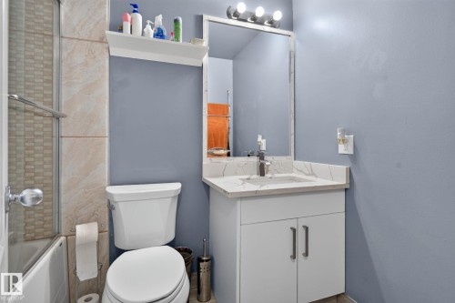 Bathroom featuring a vanity with a white countertop and integrated sink, a large wall mirror, and a three-light fixture - 1344 Lakewood Road West Nw, Edmonton, AB - Indoor Photo Showing Bathroom